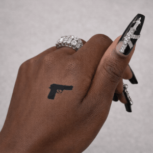 Tatouage éphémère au jagua d’un pistolet réalisé avec un pochoir, rendu bleu-noir naturel sur la peau