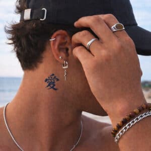 Tatouage éphémère Gaara en encre bleu foncé, motif kanji japonais signifiant amour, appliqué sur le cou d’un modèle masculin, rendu réaliste sur la peau.